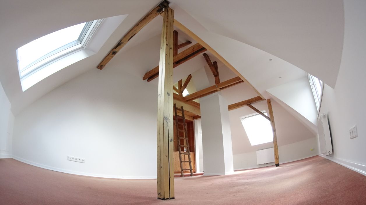 Ausgebautes Dachgeschoss mit hellen Wänden und sichtbarem Holzgebälk